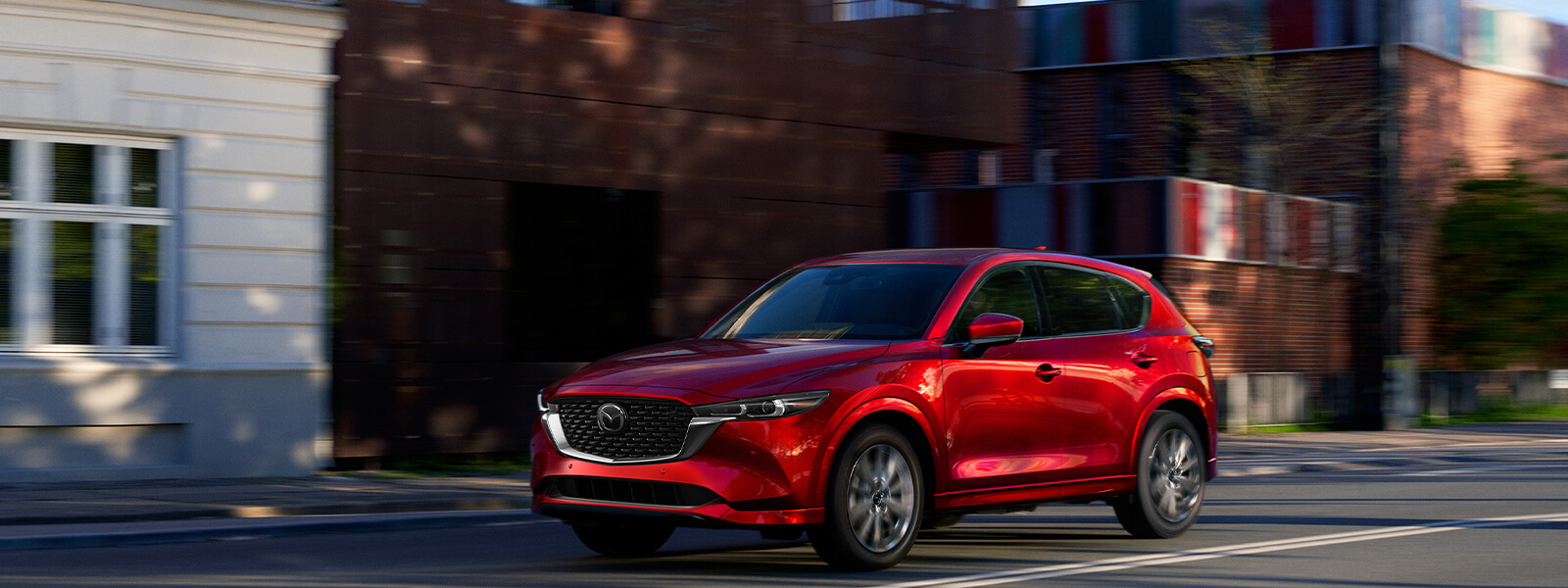 VUS Mazda rouge tournant à l’angle d’une rue pavée